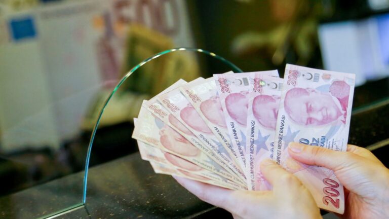 FILE PHOTO: A money changer holds Turkish lira banknotes at a currency exchange office in Ankara
